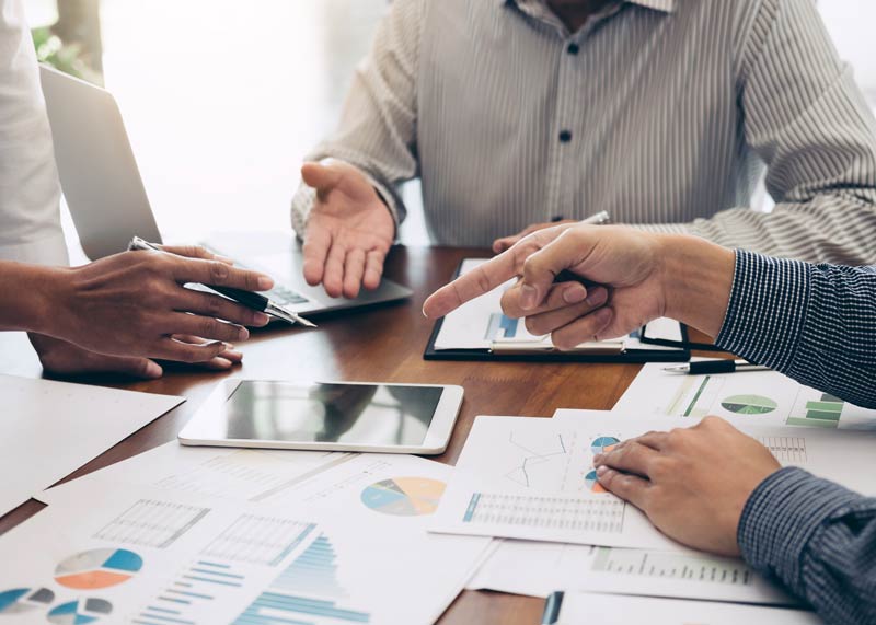 Three people around a table with charts and graphs